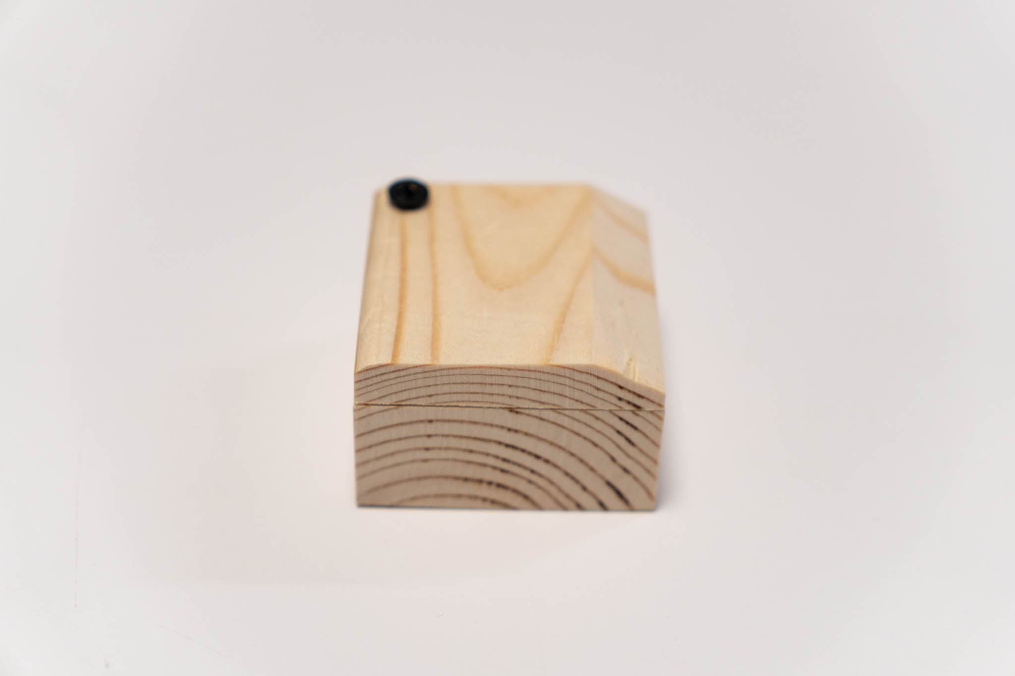 a small rectangular wooden beige box with its lid ancored at a corner, closed