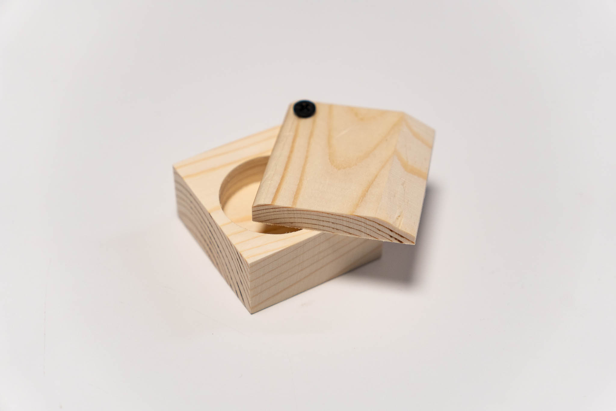 a small rectangular wooden beige box with its lid ancored at a corner, half open